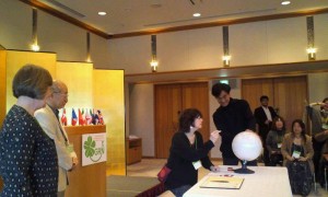 Hiroshi Doi and Jean Jones watch Audrey Pearson sign the globe as representative of the USA